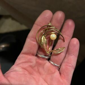 A vintage gold-tone filigree brooch with a pearl and leaf design.